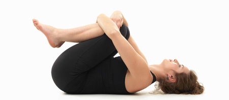 Realizando la postura de yoga llamada "Pavanamuktasana"