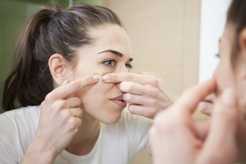 Mujer tratando de quitarse el acné es mejor consultar con un dermatólogo