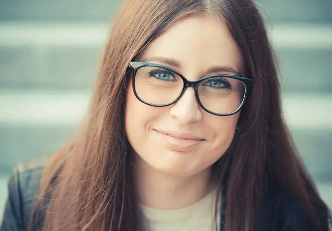 Una mujer con cara redonda que usa gafas redonda acentuando aún más sus rasgos