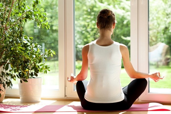 Mujer practicando yoga en casa durante la mañana