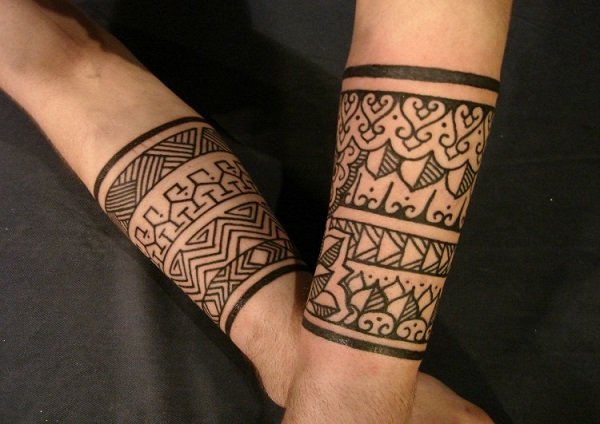 Joven con los brazos tatuados con muñequeras estilo tribal