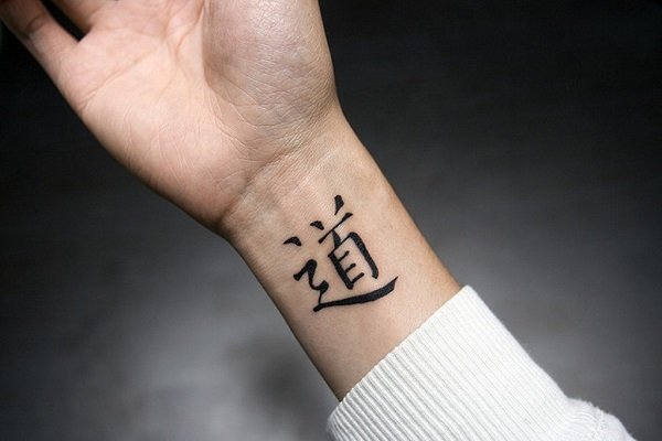 Joven hombre con un tatuaje con símbolos orientales en su brazo