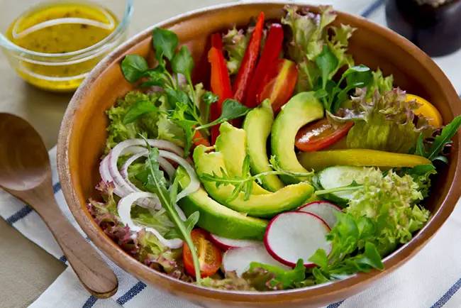 Un plato de ensalada con aguacates y verduras para eliminar las lonjas de la cintura