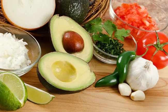 ingredientes para preparar guacamole en casa sobre una mesa de madera