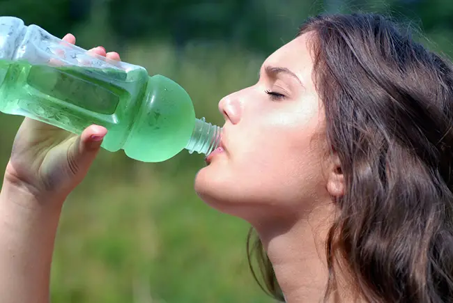 Mujer tomando agua energética por el calor que siente