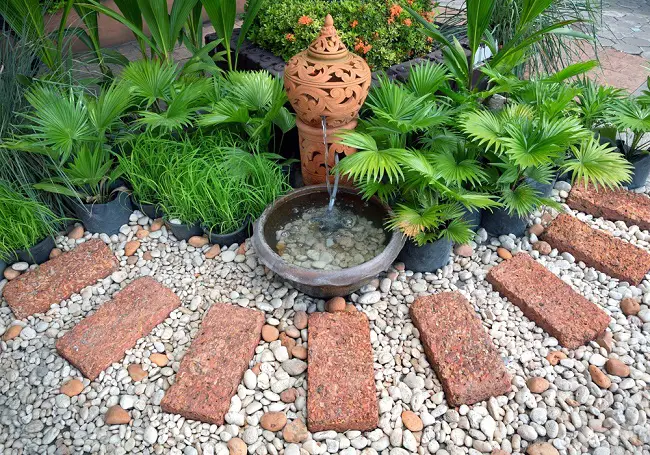 hacer jardinería en un espacio zen con piedras fuente agua