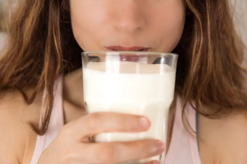 Mujer bebiendo un vaso de leche vegetal