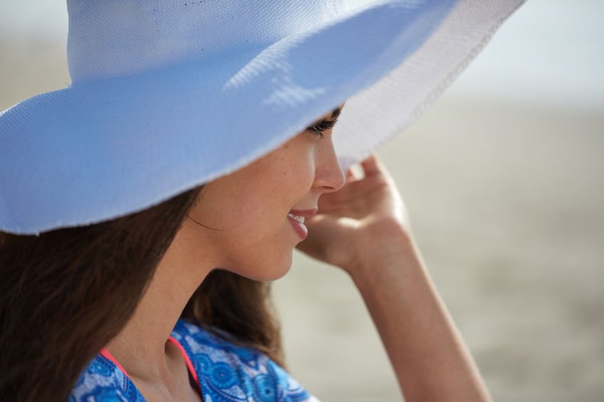 Mujer en la playa con un sombrero para prevenir el cáncer de piel