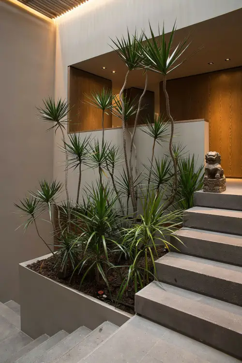 jardín iluminado debajo de la escalera a base de palma