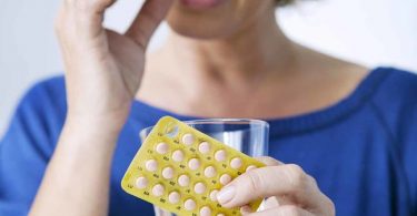 Mujer tomando cápsulas reemplazo hormonal