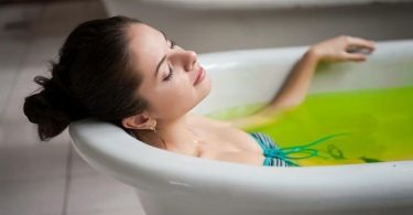 Mujer se baña en una tina con agua caliente y aceite de menta para aliviar los dolores musculares