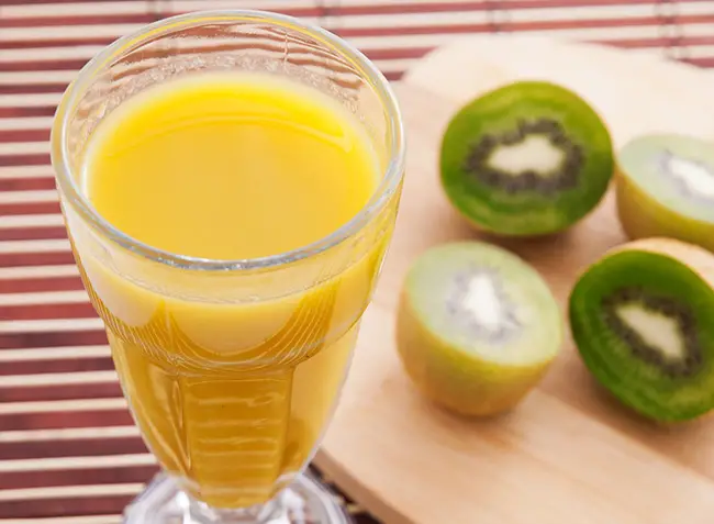 Un vaso con jugo de naranja y kiwi para aliviar los síntomas de la cistitis