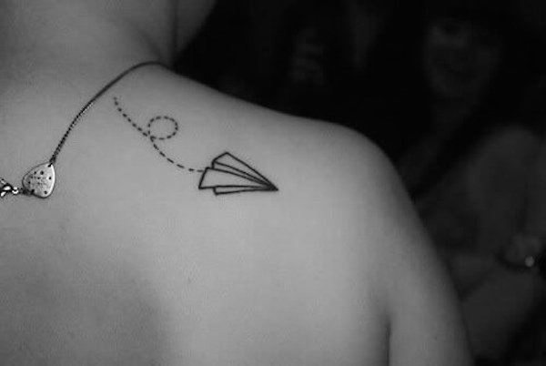 Mujer con un tatuaje de un avión de papel en su espalda