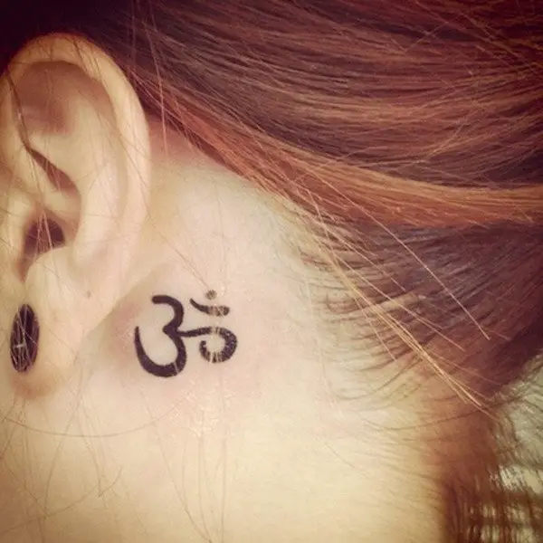 Una chica con un tatuaje detrás de la oreja con el símbolo Om