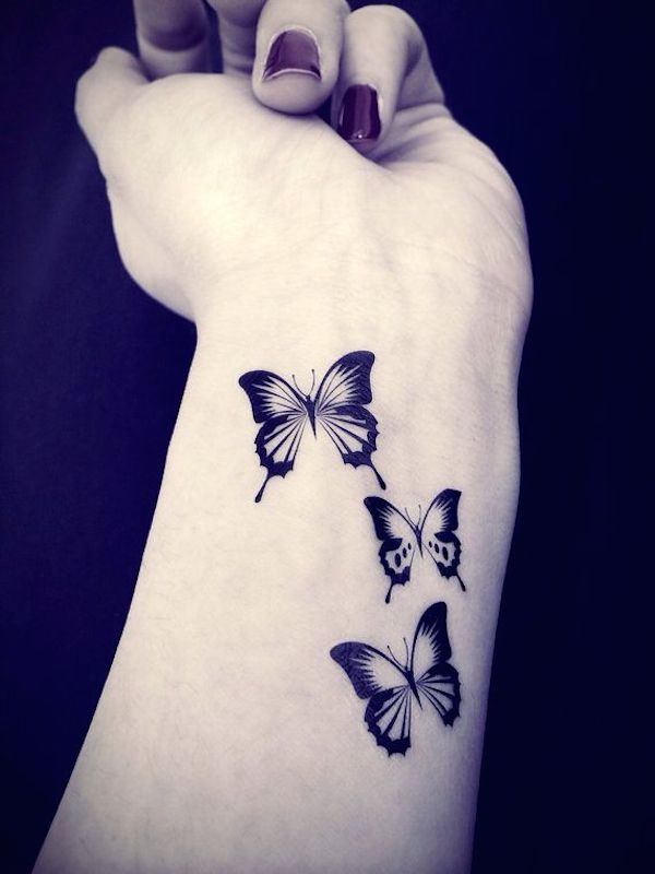 mujer con tatuaje de unas mariposas pequeñas en su antebrazo