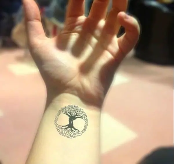 Mujer con tatuaje del árbol de la vida en su antebrazo, un símbolo pequeño pero con un significado muy grande