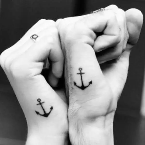 Una pareja lleva un pequeño tatuaje de dos anclas en cada una de sus manos, simbolizando la unión
