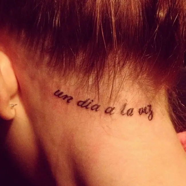 Frases tatuada en el cuello de una joven mujer de piel blanca