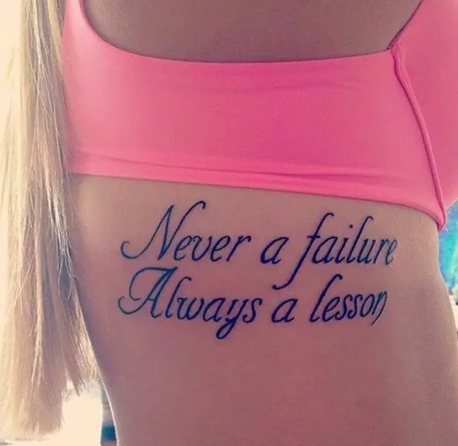 Una frase tatuada en el costdo del cuerpo en una joven mujer rubia