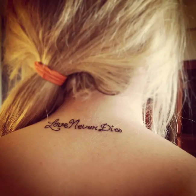 Joven mujer rubia con una frase tatuada en su espalda