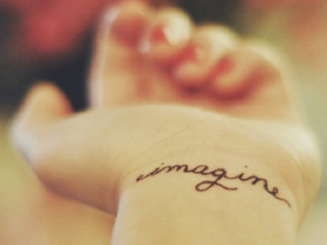 Llevando un tatuaje en su mano con la frase "imagina"