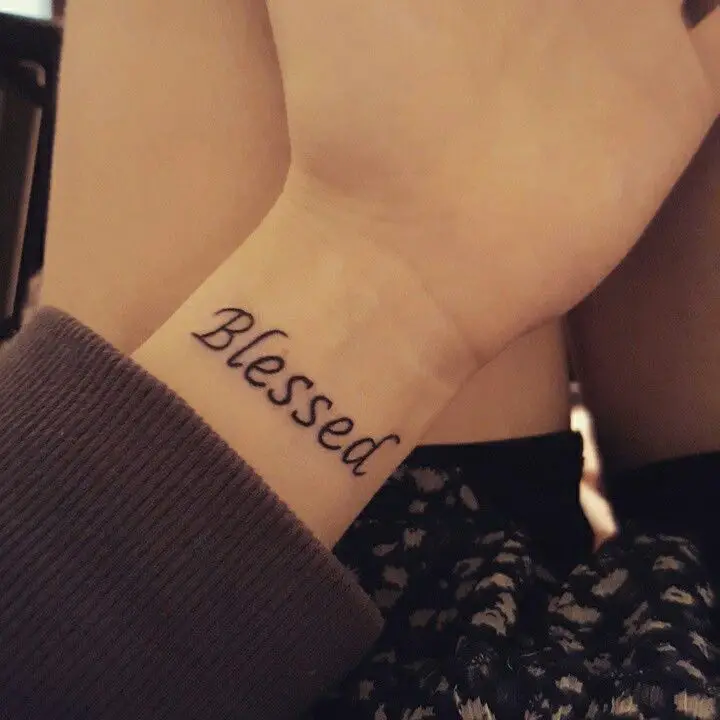 palabra bendecido tatuada en la muñeca de una mujer joven