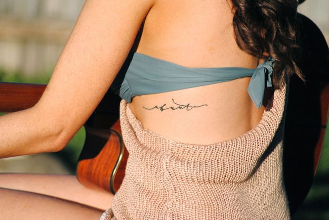 Joven mujer con un tatuaje en su espalda que dice Ubuntu