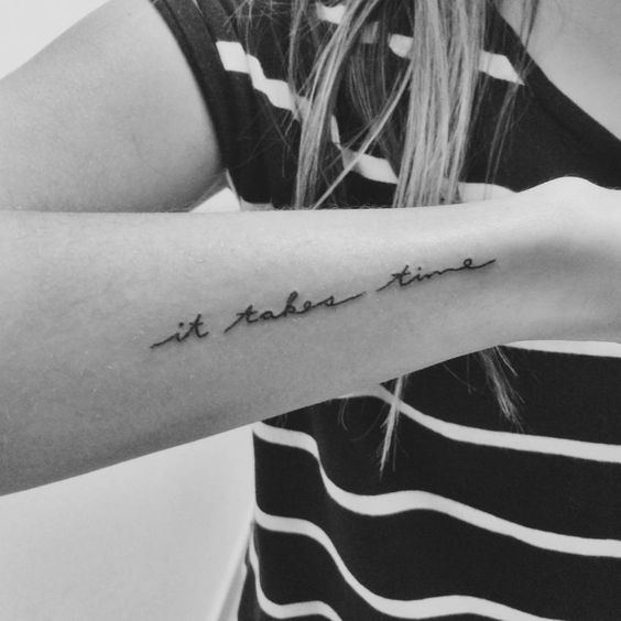 mujer con una frase tatuada en el antebrazo que dice: "Esto toma tiempo"