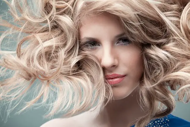 Mujer con cabello teñido de rubio y sus pelos al viento