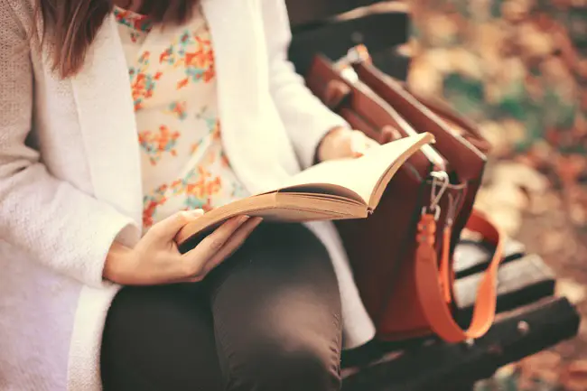 Una mujer adulta leyendo sentada en un parque