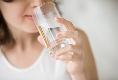 Mujer bebiendo agua tibia para beneficiarse de todas sus propiedades