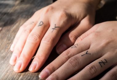 Hombre con tatuajes de petras en sus dedos
