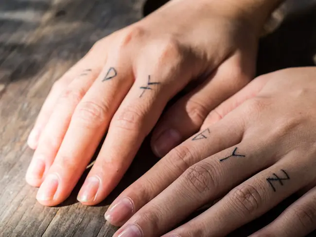 Hombre con tatuajes de petras en sus dedos