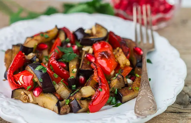 Berenjenas acompañadas con verduras servidas en un plato blanco