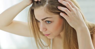 Mujer mirándose el cabello en el espejo