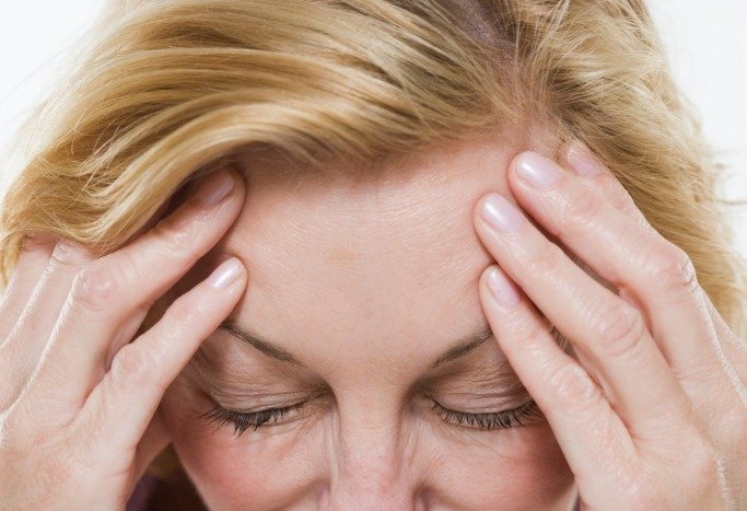 una mujer se realiza masajes en la sien para calmar el dolor de cabeza