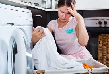 Mujer lavando la ropa en su lavadora para quitar las manchas y blanquearla