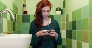 Mujer usando su telefono en el baño