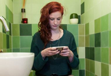 Mujer usando su telefono en el baño