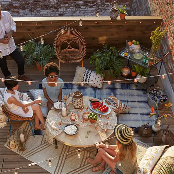 Reunión de amigos en la azotea decorada con estilo bohemio, con mesas y velas, tardeada y merienda en la terraza de la azotea.