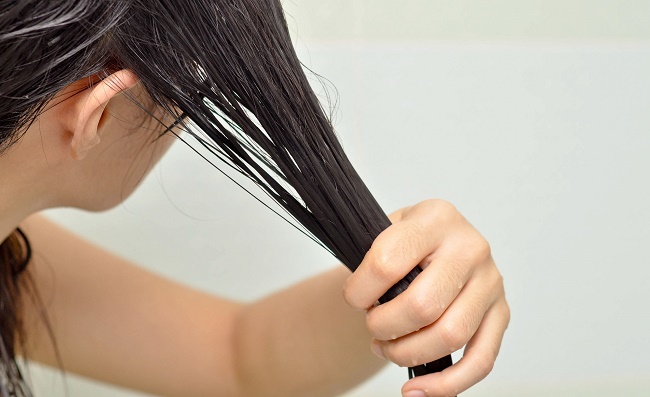 Femme effectuant un traitement avec des masques pour les cheveux abîmés