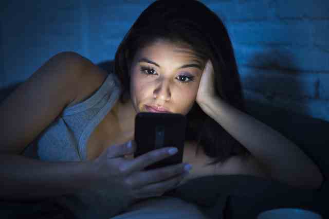 mujer con su teléfono movil en la cama