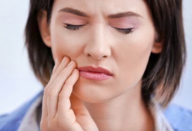 Una mujer afectada por el bruxismo que tiene dolores de cabeza y en la mandíbula