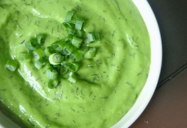 Un plato con deliciosa sopa alcalinizante de pepinos y aguacate con cebollines decorando