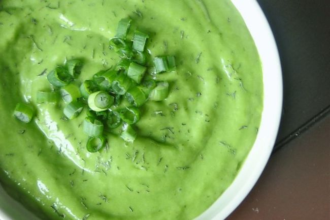Un plato con deliciosa sopa alcalinizante de pepinos y aguacate con cebollines decorando