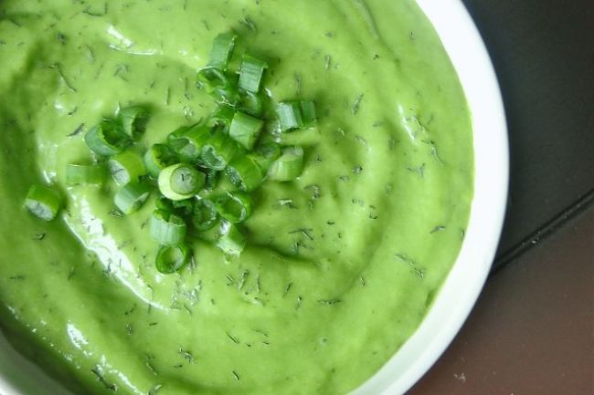 Un plato con deliciosa sopa para alcalinizar de pepinos y aguacate con cebollines decorando