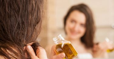 Mujer aplicando aceite de germen de trigo en su cabello