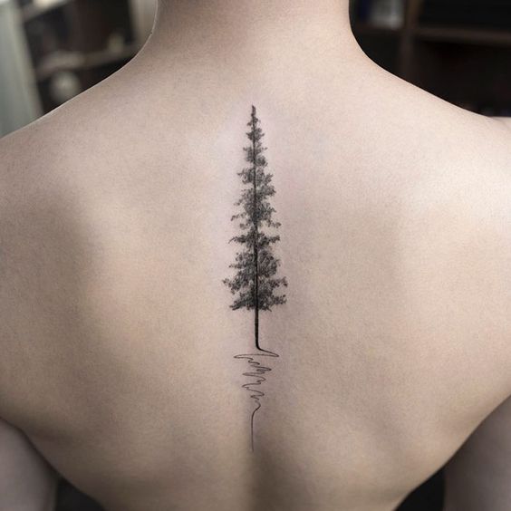 Un pino como un tatuaje en la parte media de la espalda de una joven mujer