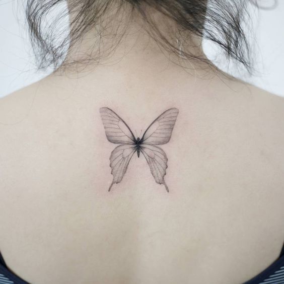 Una mariposa transparente tatuada en la espalda