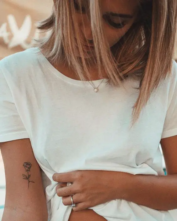 Chica rubia con muna flor tatuada en el brazo